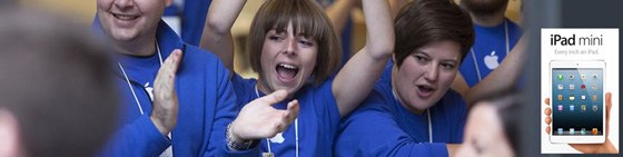 A banner with a crowd of people wearing blue Apple store uniforms cheering and clapping, with a cutout of a hand holding an iPad in the corner, under the words "iPad mini".