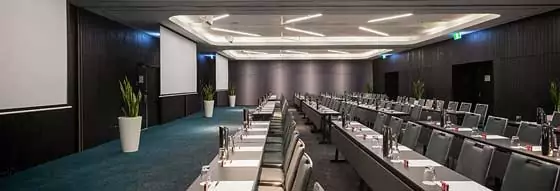 A modern conference room with rows of empty chairs in front of drop-down screens.