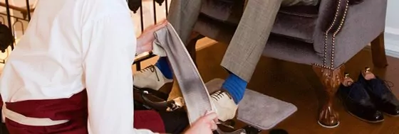 A close-up shot of a man polishing another man's shows with a white cloth.