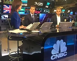 Three newsreaders seated at the CNBC news desk.