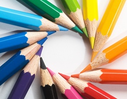 A close-up of sharpened pencil tips, arranged in a circular rainbow.