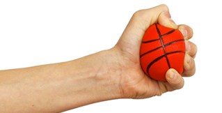 A hand squeezes a stress ball that looks like a basketball.
