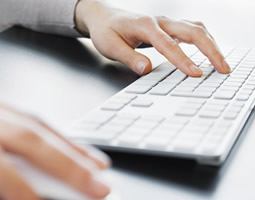 A close up of hands typing at a keyboard.