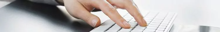 A close up of hands typing at a keyboard.