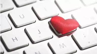 A close up of a keyboard with a red heart on one key.