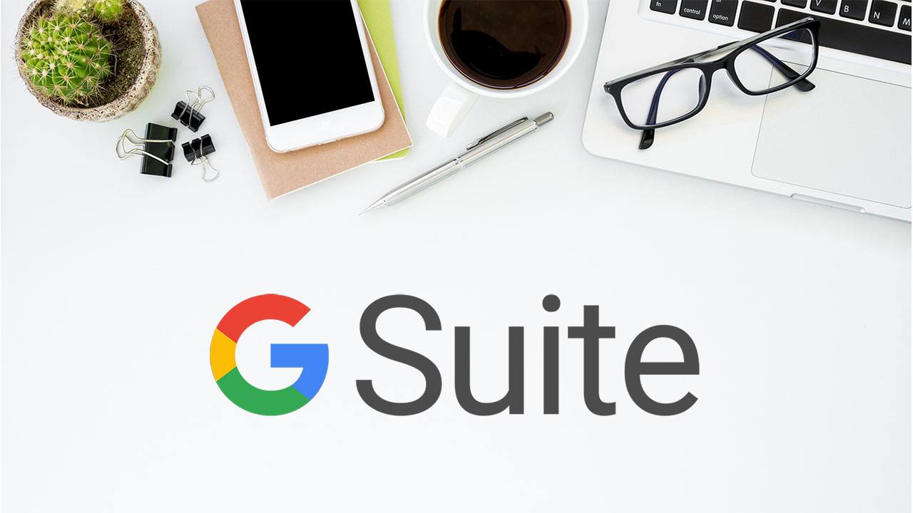 A birds-eye-view of a desk with various stationary and tech visible, with the GSuite logo below.