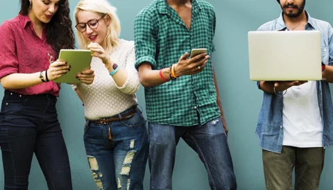 A diverse group of people standing and looking at their smart devices