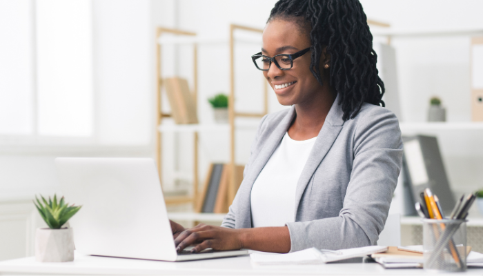 A lady sitting at her desk working on her laptop and looking very engaged.