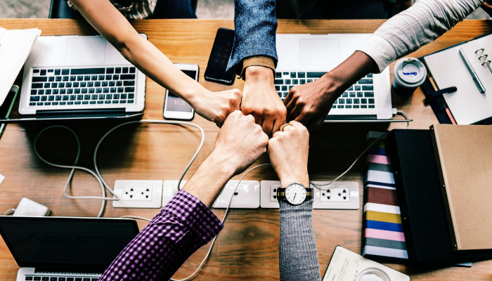 Close up top view of business people putting their hands together, showing teamwork and unity